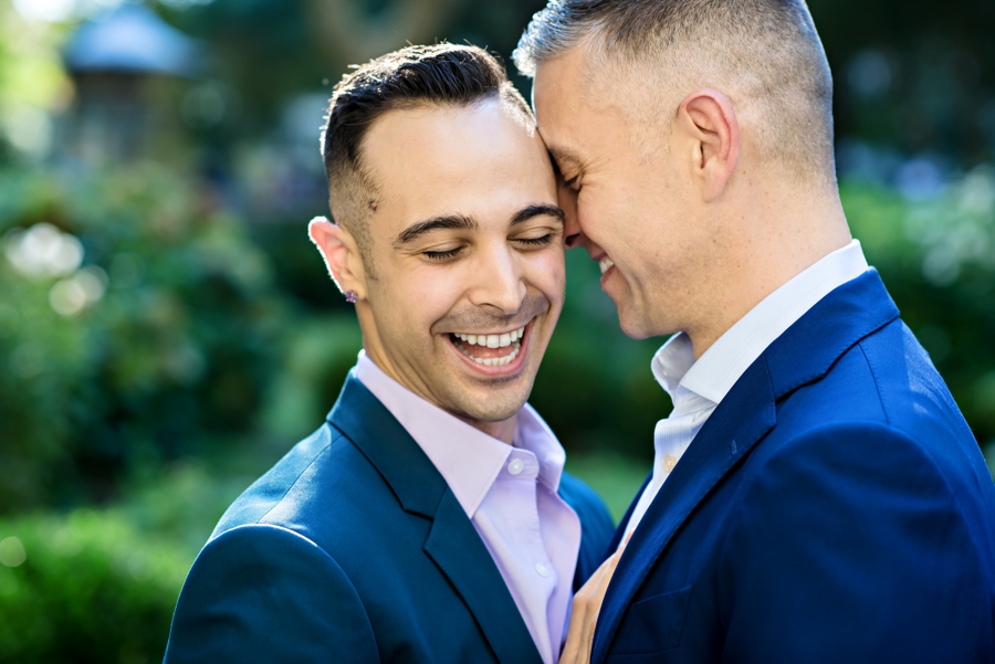 A man laughs while his fiance whispers into his ear during their Philly Engagement Session.